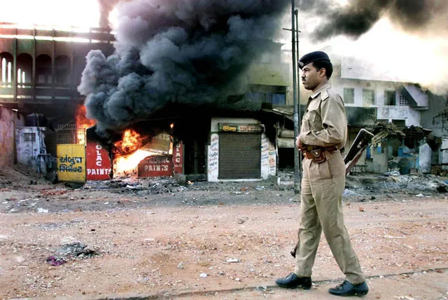 an indian policeman looks on as a row of shops burn in ahmedabad during religious riots in gujarat in 2002 photo afp file an indian policeman looks on as a row of shops burn in ahmedabad during religious riots in gujarat in 2002 photo afp file