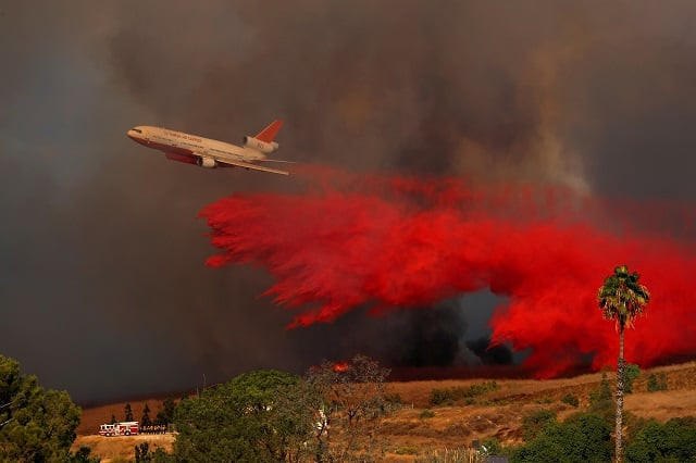 a dc 10 aircraft drops fire retardant on a wind driven wildfire in orange california us photo reuters