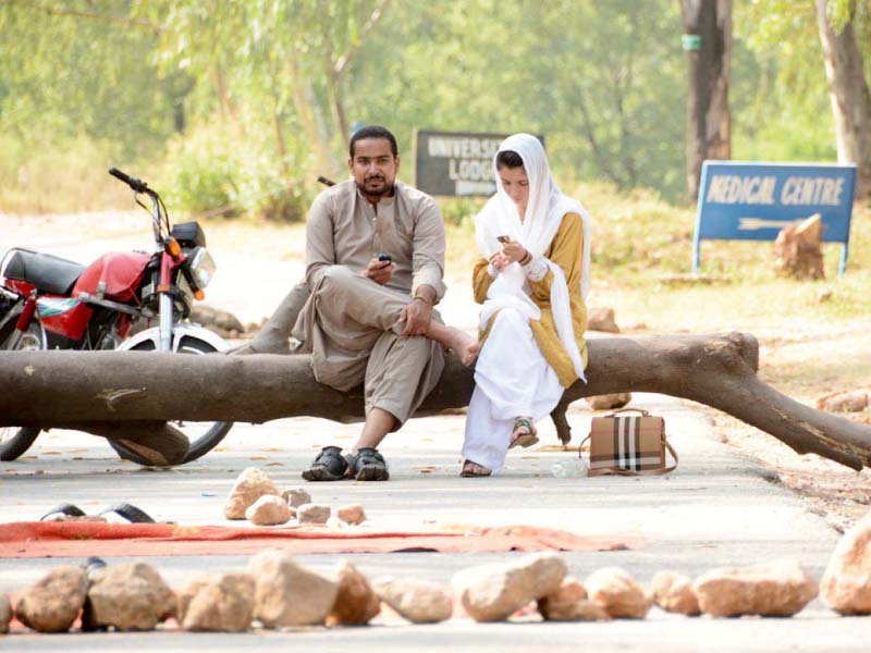 students sit on a barricade at qau photo online
