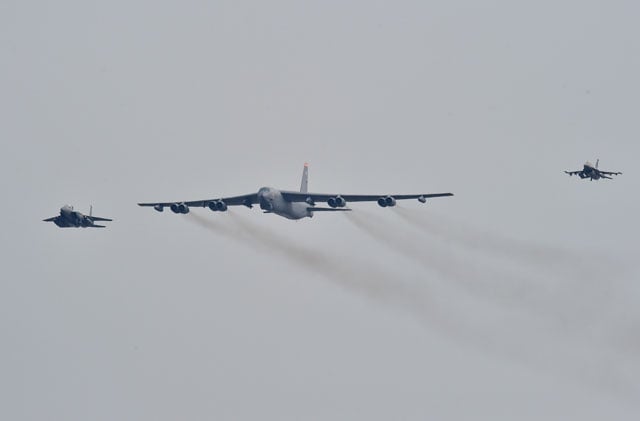 a us b 52 stratofortress c is escorted by a south korean f 15k fighter jet l and a us f 16 fighter jet r as it flies over the osan air base in pyeongtaek south of seoul on january 10 2016 photo afp