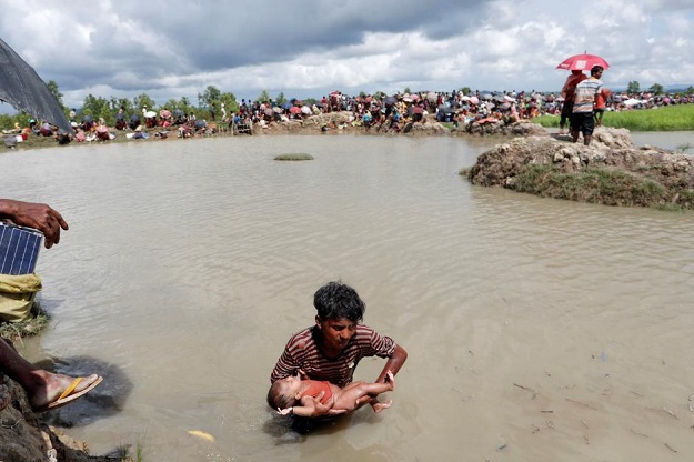 a rohingya refugees walks with a baby in a rice field after crossing the border in palang khali bangladesh october 9 2017 photo reuters