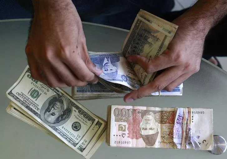 a currency dealer counts pakistani rupees and u s dollars at his shop in karachi photo reuters a currency dealer counts pakistani rupees and u s dollars at his shop in karachi photo reuters