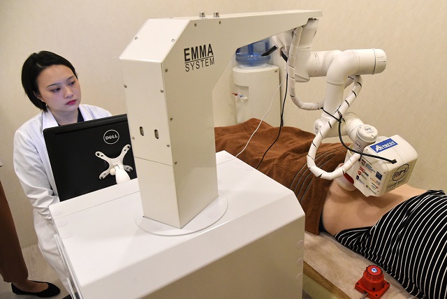 in this photo taken on october 12 2017 singaporean physician calista lim hui min l monitors progress as a robot masseuse named emma massages patient elaine low 35 at the novahealth traditional chinese medicine tcm clinic in singapore a robot masseuse named emma is offering singaporeans high tech back rubs with a gigantic metal arm and warm silicon tips which its creators say perfectly mimic the human touch the robot the brainchild of local startup aitreat began work at a clinic in the city state this week and performs quot tui na quot a type of massage practised in traditional chinese medicine photo afp