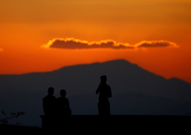 boys watch atop the roof of their house on the turkish syrian border line in reyhanli hatay province turkey photo reuters