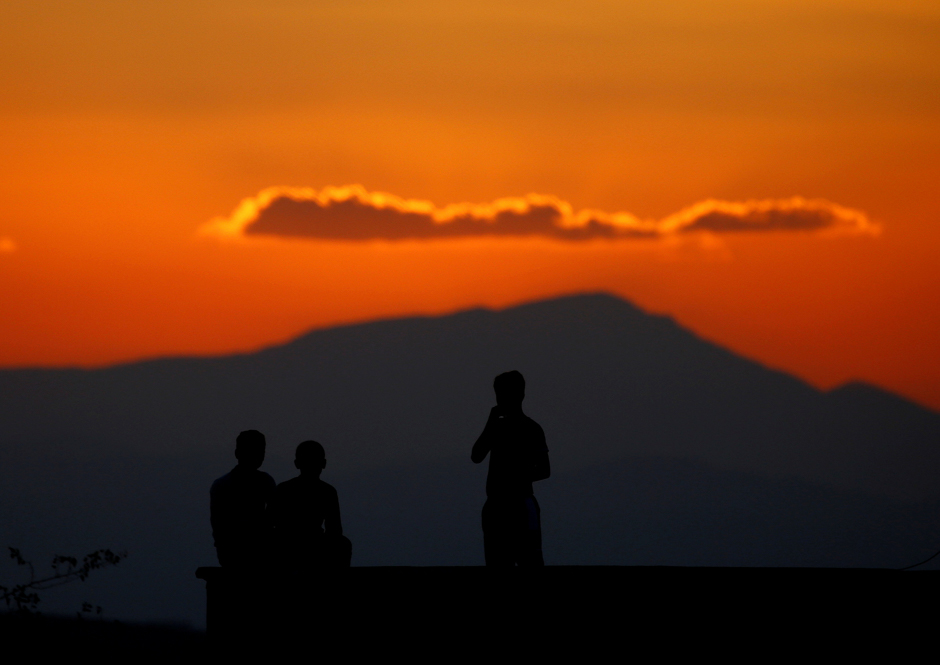 boys watch atop the roof of their house on the turkish syrian border line in reyhanli hatay province turkey photo reuters