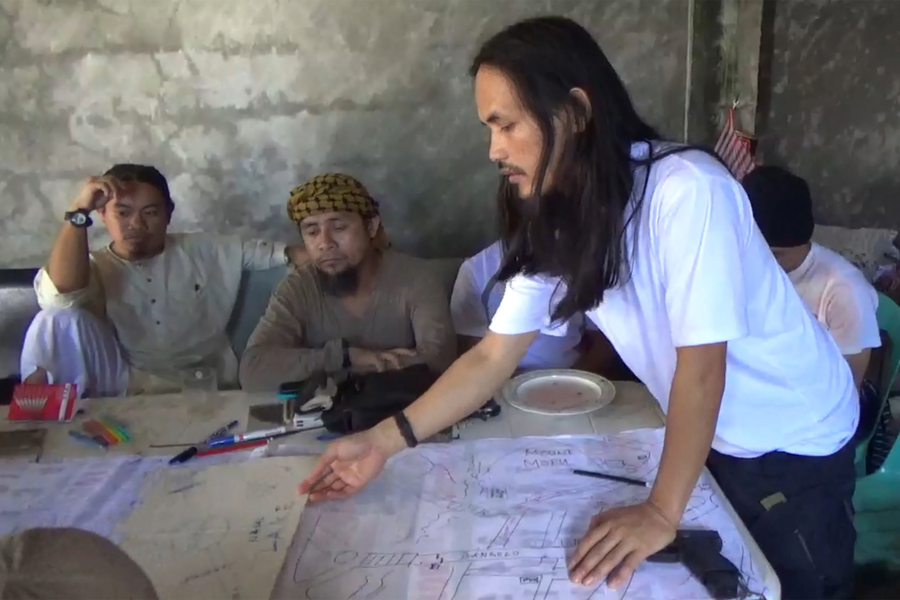 isnilon hapilon 2nd l leader of the hardline abu sayyaf group looking on at an improvised map of marawi photo afp