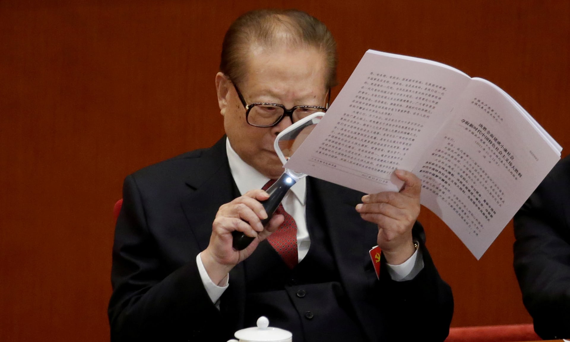 former chinese president jiang zemin uses a magnifying glass to read chinese president xi jinping s report during the opening of the 19th national congress of the communist party of china photo reuters
