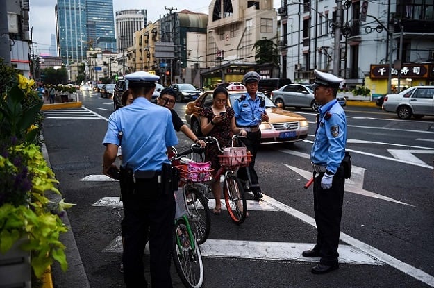 in this photograph taken on august 9 2017 chinese traffic policemen stop a group of people riding bicycles and offending traffic rules next to the installed facial recognition screen at a road intersection in shanghai from toilet paper dispensers to fast food restaurants travel and crime fighting china is taking the lead in rolling out facial recognition technology afp photo chandan khanna to go with story china lifestyle economy technology security facial focus by peter stebbings photo afp