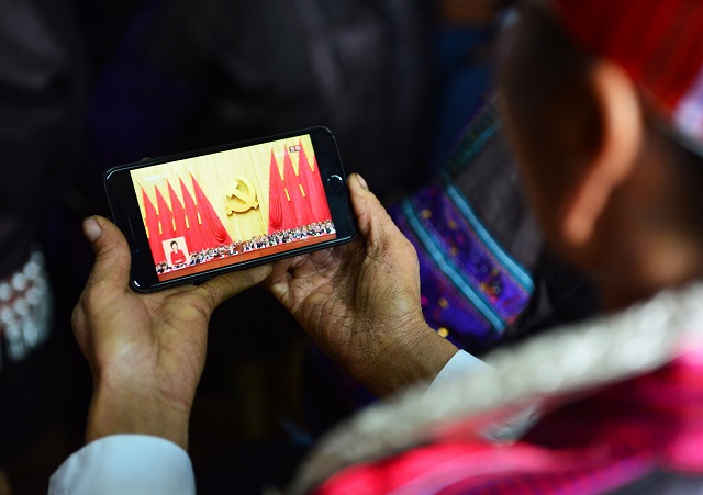 this photo taken on october 18 2017 shows a woman of the dong ethnic minority watching the opening session of the 19th communist party congress on a smart phone in jianhe in china 039 s southwestern guizhou province president xi jinping declared china is entering a quot new era quot of challenges and opportunities on october 18 as he opened a communist party congress expected to enhance his already formidable power photo afp