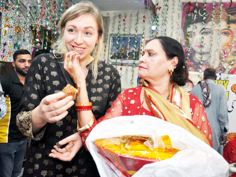 a woman distributes sweets among the guests during diwali photo abid nawaz express