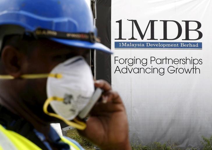 a construction worker talks on the phone in front of a 1malaysia development berhad 1mdb billboard photo reuters