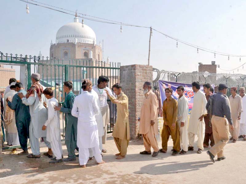 devotees stand in a queue waiting for their turn to enter the shrine photo online