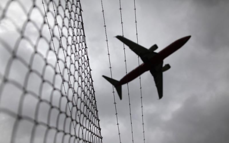 a passenger plane flies over a barbed wire fence photo reuters