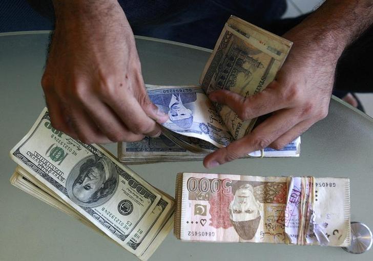 a currency dealer counts pakistani rupees and u s dollars at his shop in karachi photo reuters