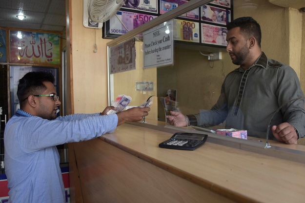 a visiting dual kashmiri and british citizenship holder l exchanging british pounds at a remittance shop in the azad jammu and kashmir city of mirpur which is known as quot little england quot photo afp