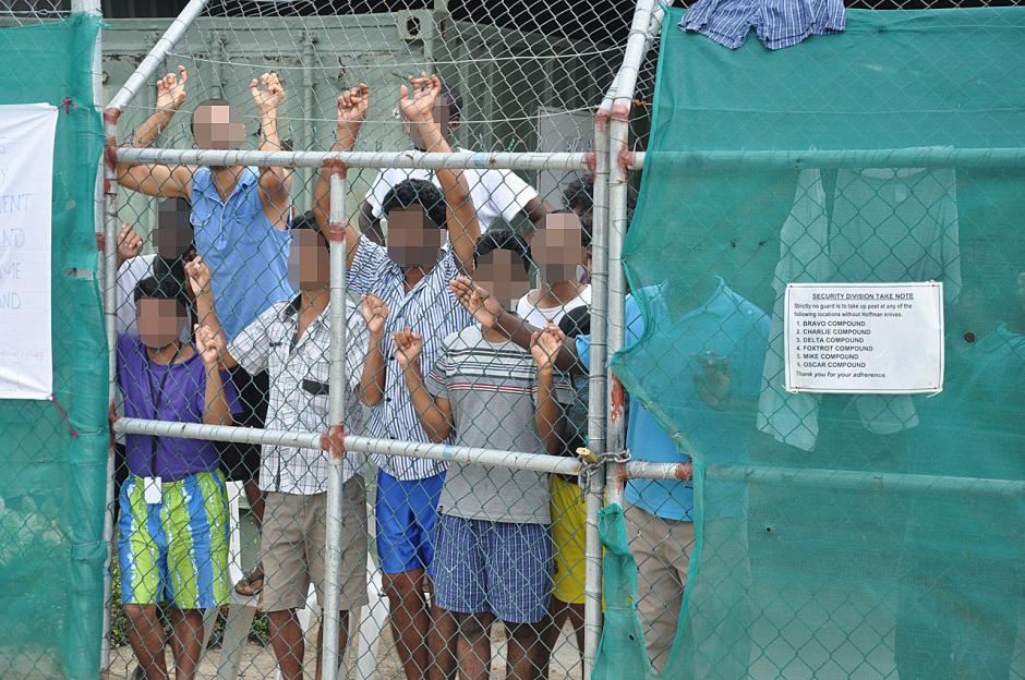 asylum seekers look through a fence at the manus island detention centre in papua new guinea aap eoin blackwell via reuters