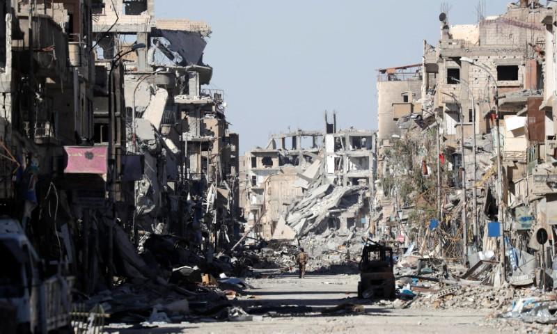 a fighter of syrian democratic forces stands amidst the ruins of buildings near the clock square in raqqa photo reuters