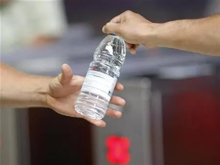a man hands a bottle of water to another man photo reuters a man hands a bottle of water to another man photo reuters