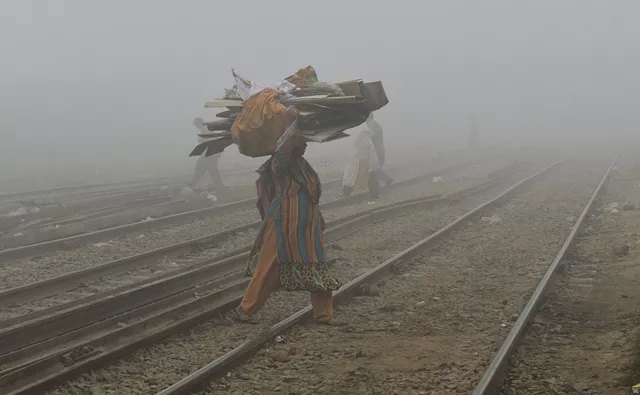 a woman holds a cardboard on her head as she crosses a rail track in heavy smog in lahore photo afp a woman holds a cardboard on her head as she crosses a rail track in heavy smog in lahore photo afp