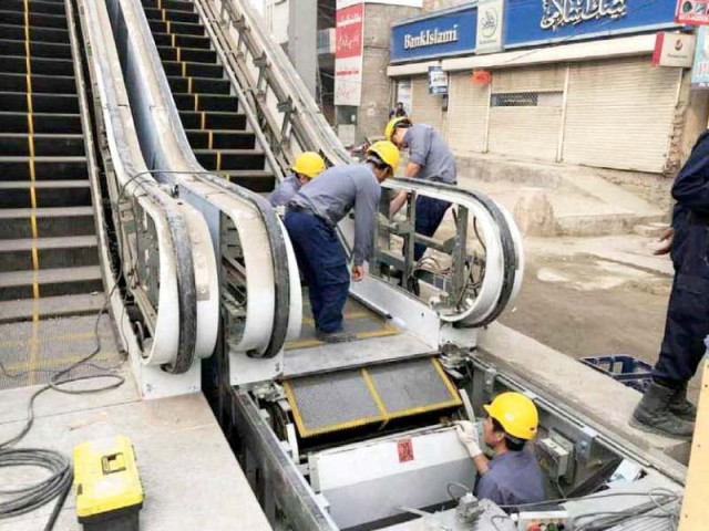 engineers install an escalator at the orange line metro train station on gt road on wednesday photo express engineers install an escalator at the orange line metro train station on gt road on wednesday photo express