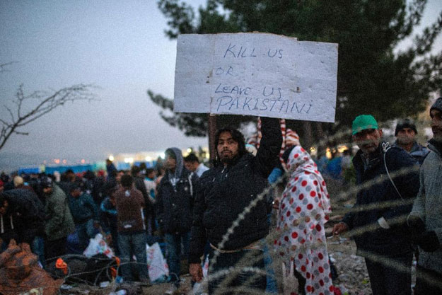 a migrant from pakistan holds a placard as he waits with other migrants and refugees to cross the greek macedonian border near gevgelija photo file