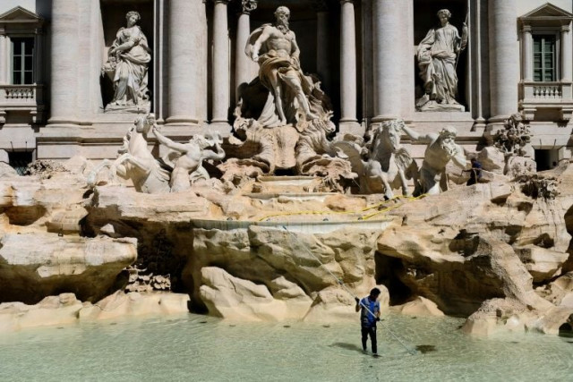 a worker collects coins tossed into the trevi fountain in rome as part of a regular monthly cleaning routine a worker collects coins tossed into the trevi fountain in rome as part of a regular monthly cleaning routine