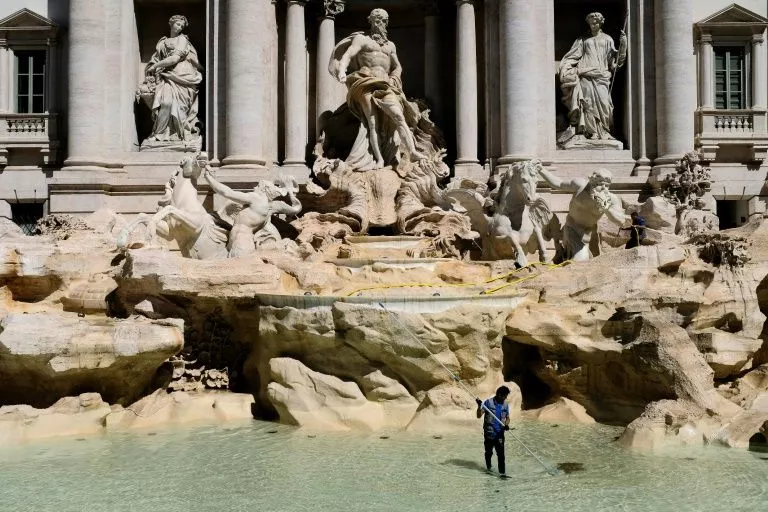 a worker collects coins tossed into the trevi fountain in rome as part of a regular monthly cleaning routine a worker collects coins tossed into the trevi fountain in rome as part of a regular monthly cleaning routine