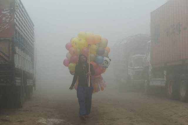 a pakistani vendor carries baloons on a street amid heavy smog in lahore photo afp