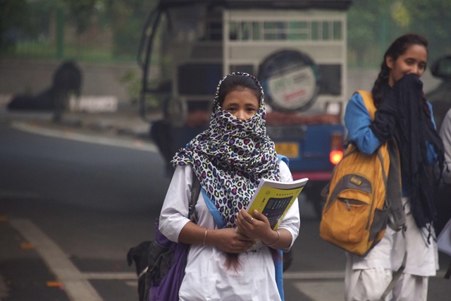 an indian girl with her face covered walks amid heavy smog on a street in new delhi on november 13 2017 photo afp