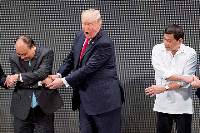 as other people clutched the person to their left and their right us president donald trump c used both of his hands to clasp the extended fingers of vietnam 039 s prime minister nguyen xuan phuc l photo afp