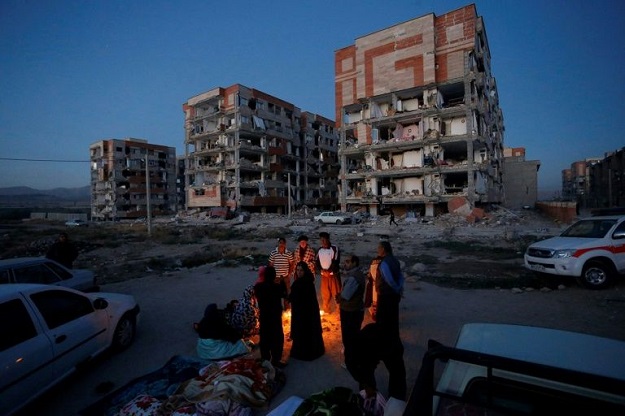 quake survivors huddle by a fire as temperatures drop in sar e pol e zahab in western iran photo afp