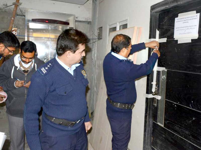 officials put up notices on doors of unapproved buildings in sector e 11 photo express