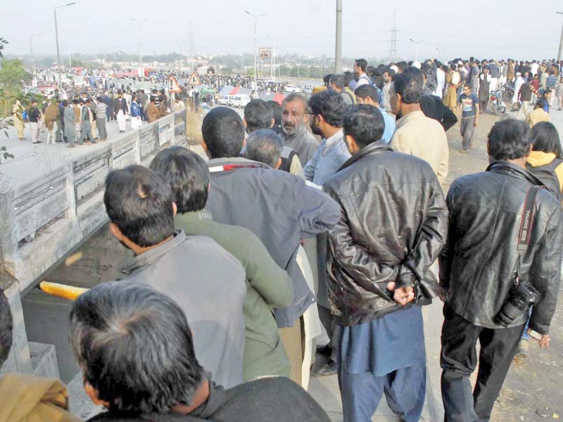 people gather to catch a glimpse of protesters sitting at faizabad photo online