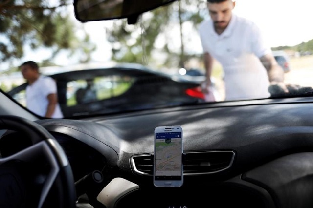 an uber driver cleans his car as his cell phone shows the queue to pick up passengers departing guarulhos international airport in sao paulo brazil february 13 2017 photo reuters