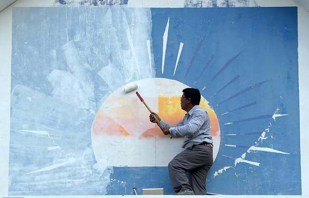 a supporter of the opposition cambodia national rescue party paints over the party logo at its headquarters after the party was banned photo afp