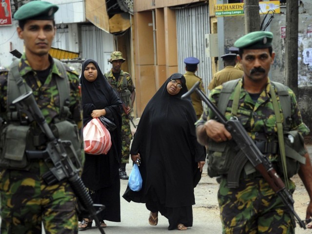 two muslim women walk behind patrolling special task force commandos outside a vandalised mosque in colombo august 11 2013 photo reuters