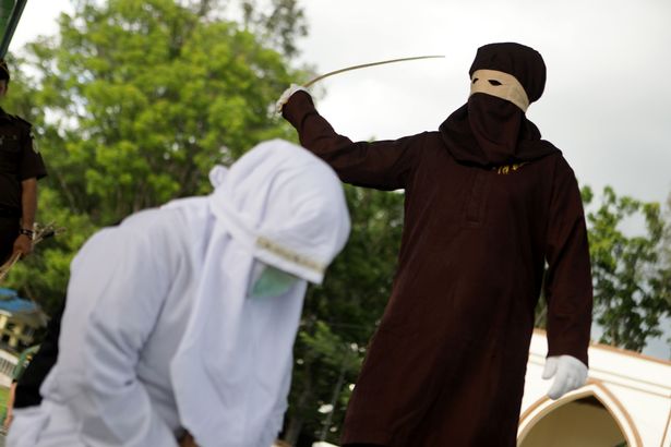 shocking images surface of indonesian woman being whipped by masked sharia enforcer