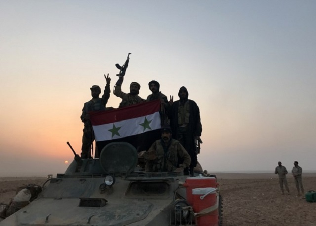 syrian forces gestures as they carry the national flag in the village of suway 039 iah near the syrian border town of albu kamal on november 9 2017 photo afp