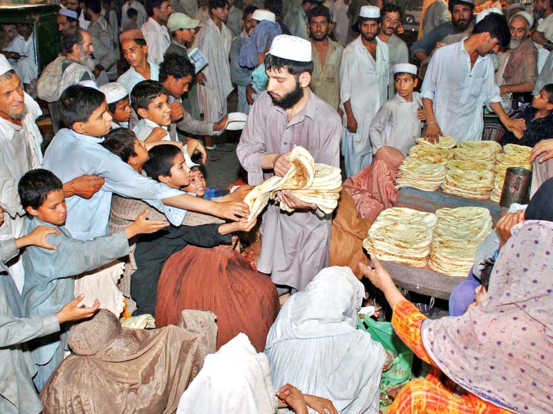 a beggar woman sits with her children while others get free food photo iqbal haider express