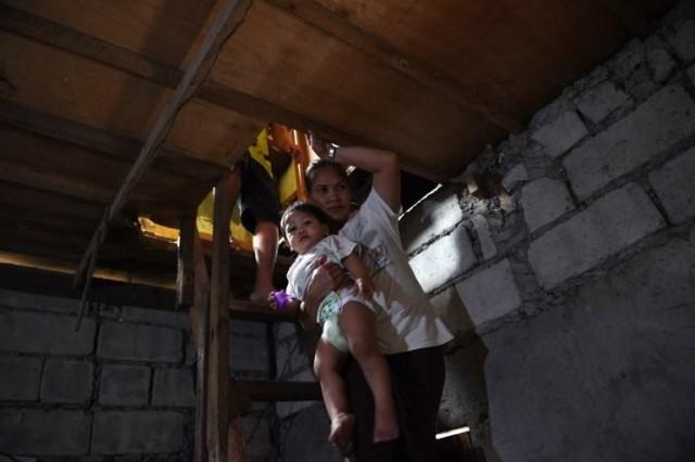 this photo taken on october 10 2017 shows myrna albos 33 carrying her child as she walks down to their house in a slum area in manila photo afp