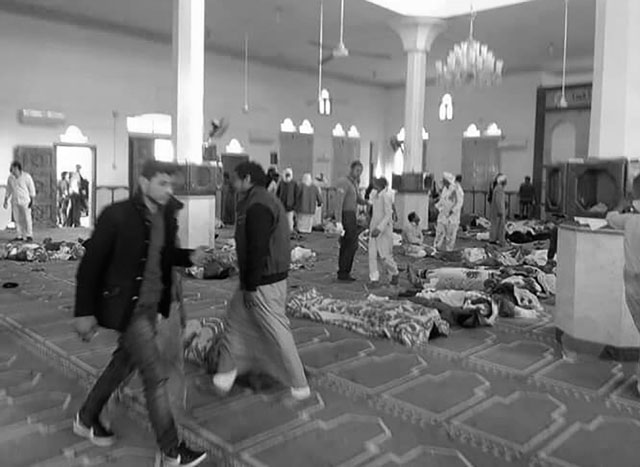 egyptians walk past bodies following a gun and bombing attack at the rawda mosque roughly 40 kilometres west of the north sinai capital of el arish on november 24 2017 photo afp