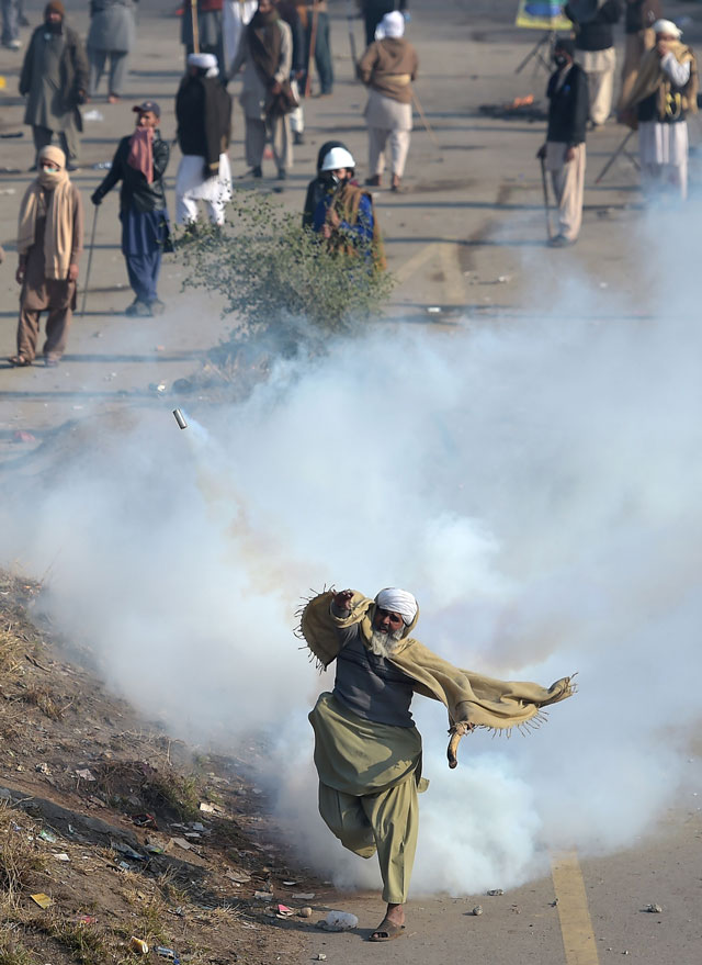 a protester of the tehreeke labaik throws a tear gas shell back towards police during a clash in islamabad on november 25 2017 photo afp