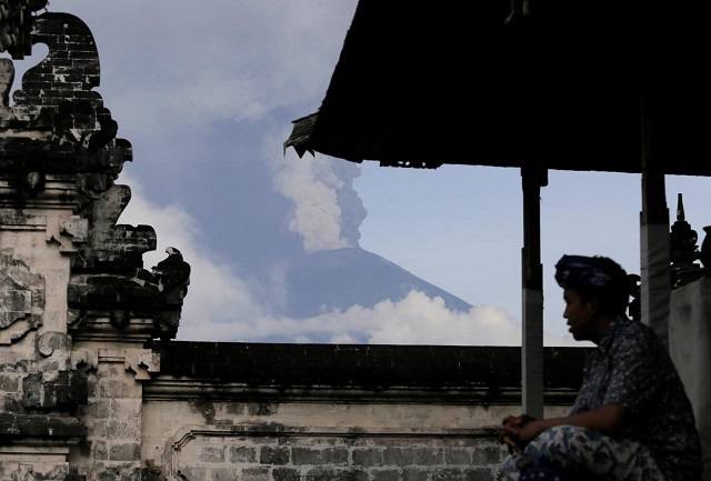 a balinese man sits as mount agung volcano erupts at lempuyang temple in karangasem bali indonesia november 27 2017 photo reuters