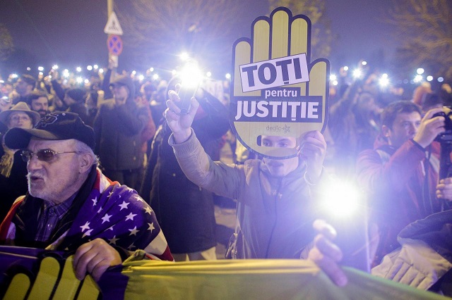 a protester holds a phone and a sign that reads quot all for justice quot while attending a rally against a plan by the ruling social democrats to overhaul the judiciary in bucharest romania november 26 2017 photo via reuters