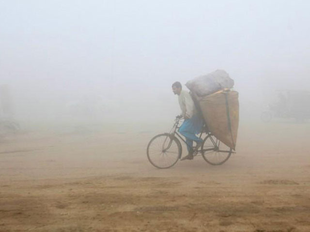 a man rides a bicycle carrying sacks of recyclables amid morning smog in lahore photo reuters