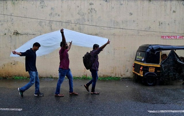 men use a plastic sheet to cover from rain as they walk along a road in kochi india may 30 2017 photo reuters men use a plastic sheet to cover from rain as they walk along a road in kochi india may 30 2017 photo reuters