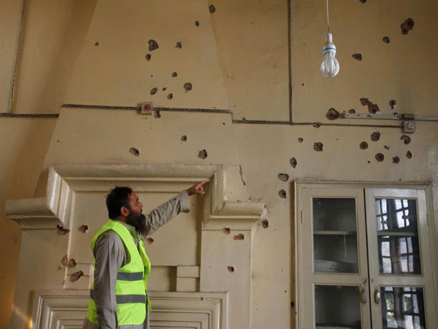 a rescue worker gestures toward bullet holes in the wall of a computer lab after the shooting at directorate of agriculture institute in peshawar december 1 2017 photo reuters