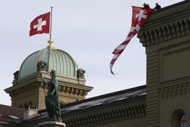 workers hang up a swiss flag on the swiss parliament building in bern switzerland photo reuters workers hang up a swiss flag on the swiss parliament building in bern switzerland photo reuters