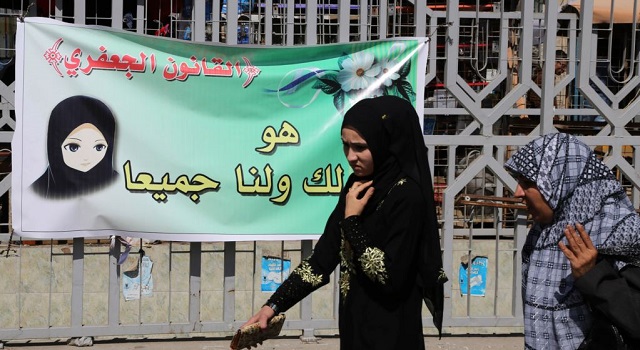 females pass by a banner in baghdad iraq photo afp