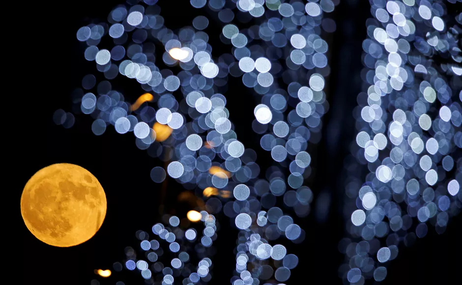 the full moon is pictured behind christmas lights in marseille france photo reuters